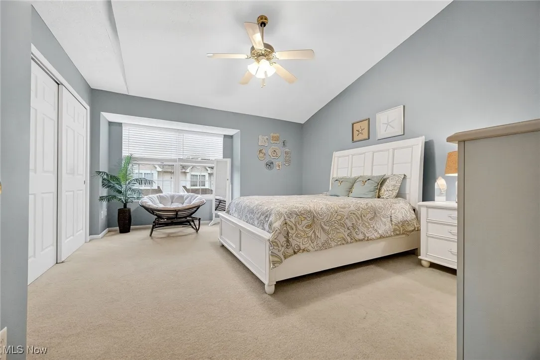 Bedroom with light colored carpet, a ceiling fan, a closet, and lofted ceiling
