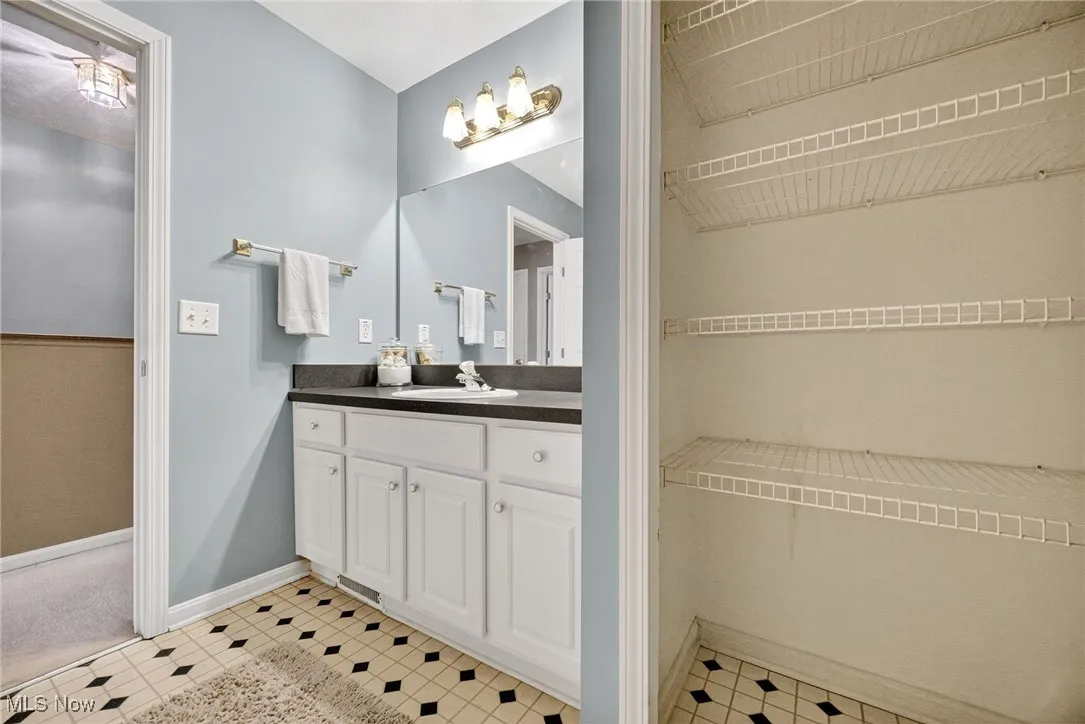 Bathroom featuring vanity, a walk in closet, and light tile patterned floors