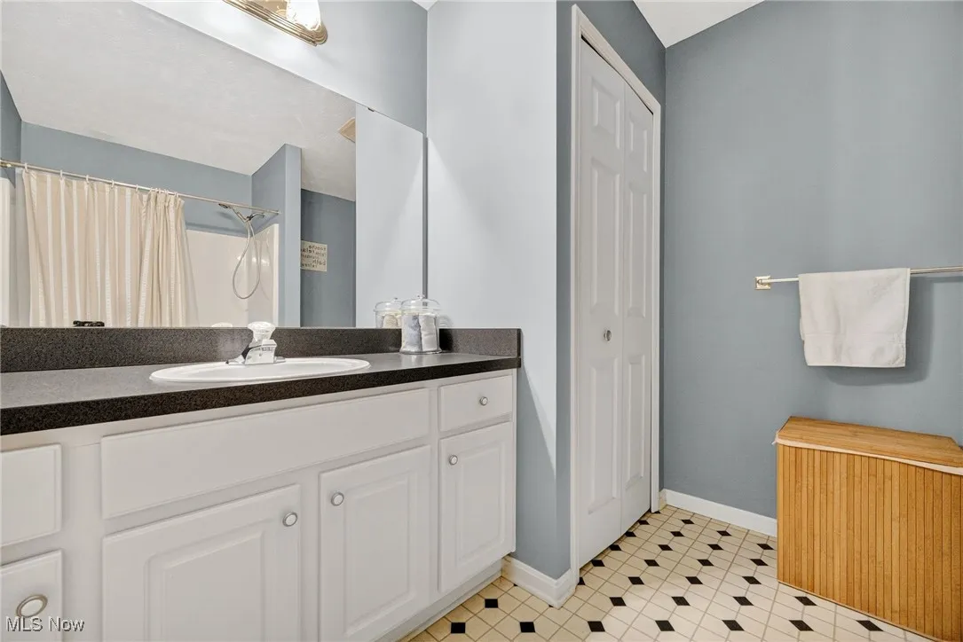 Bathroom with a closet, vanity, and a shower with shower curtain
