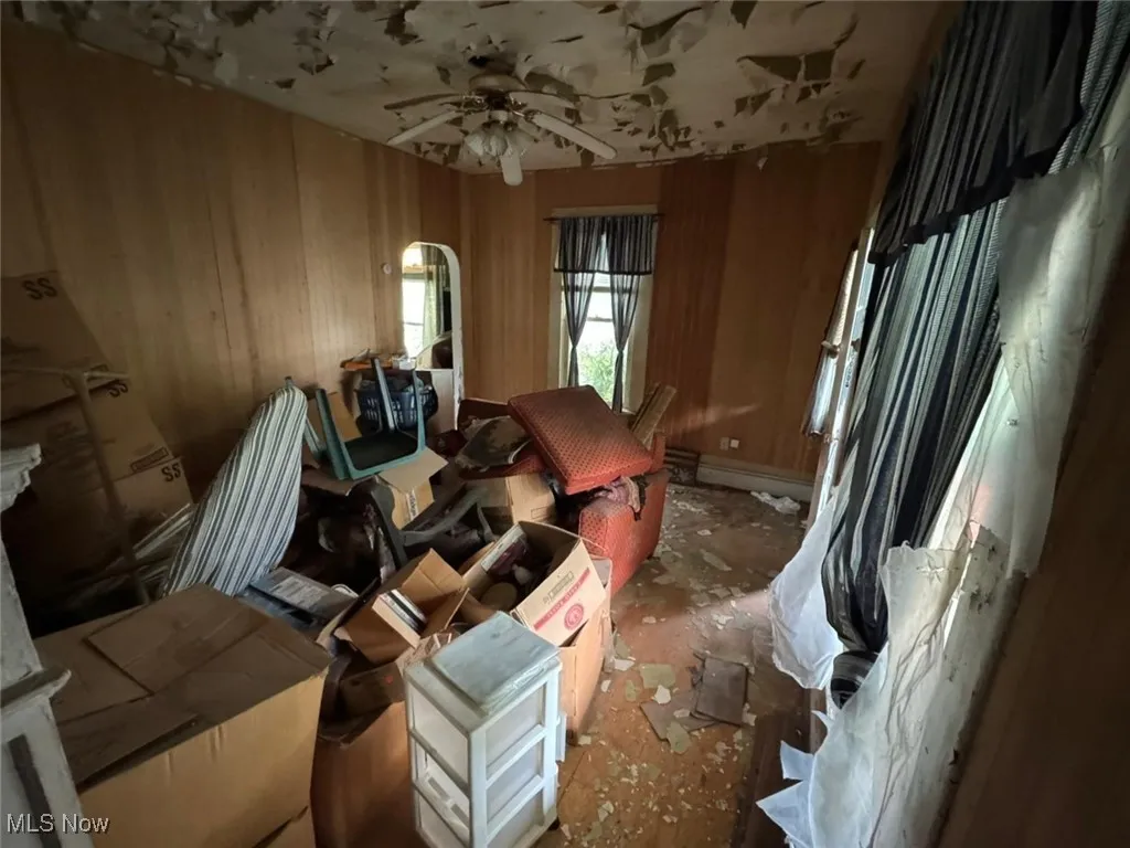 Miscellaneous room with ceiling fan and wood walls