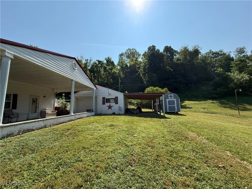 View of green lawn featuring a shed and an attached carport