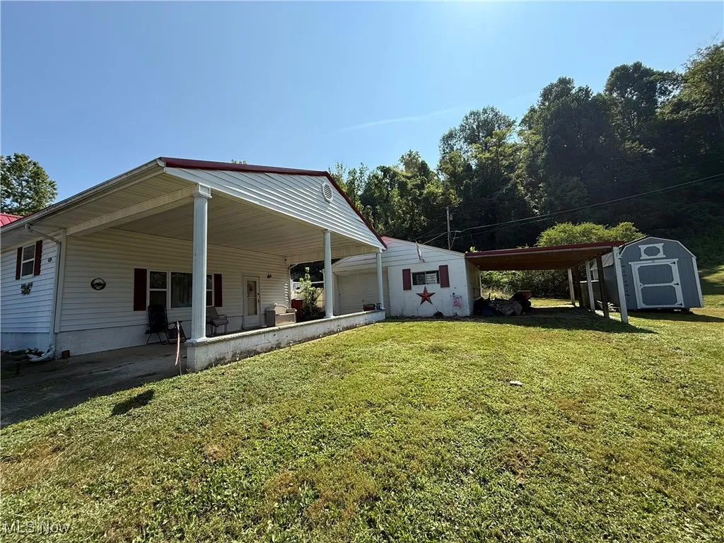 View of front facade with a storage unit, an attached carport, and a front yard