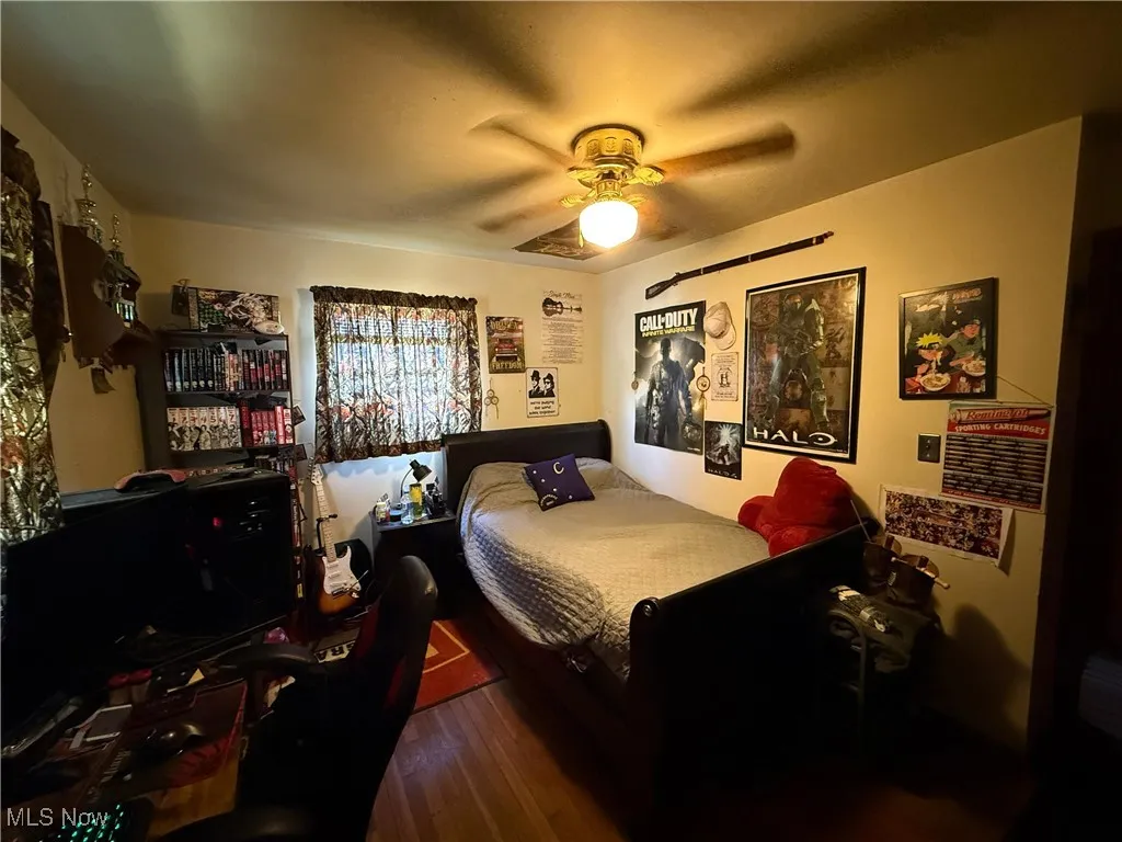 Bedroom featuring dark wood-style flooring, a ceiling fan, and a desk