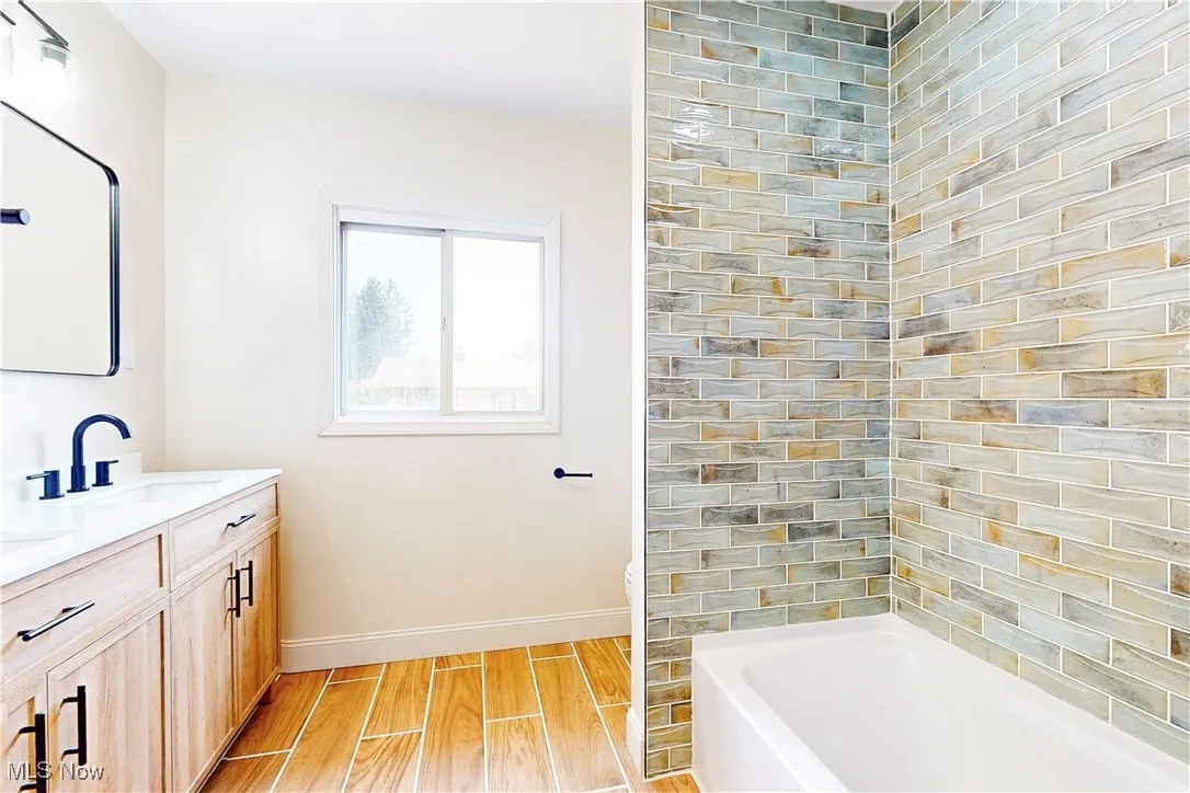 Full bathroom featuring wood tiled floors, vanity, and tub / shower combination