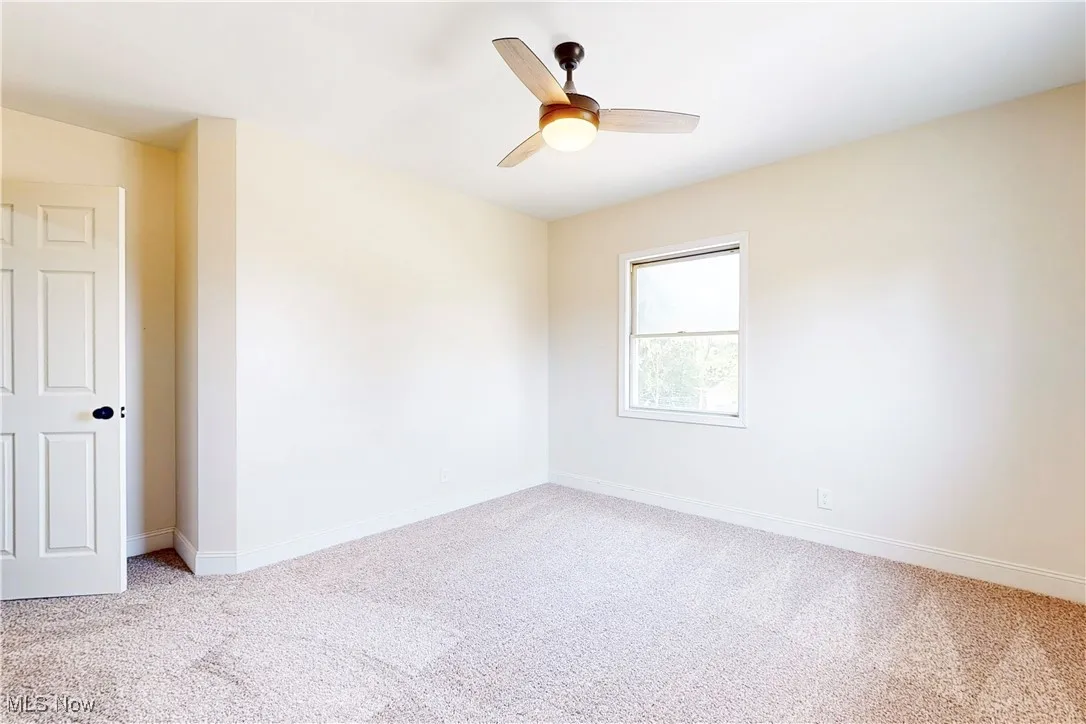 Empty room with light carpet and ceiling fan