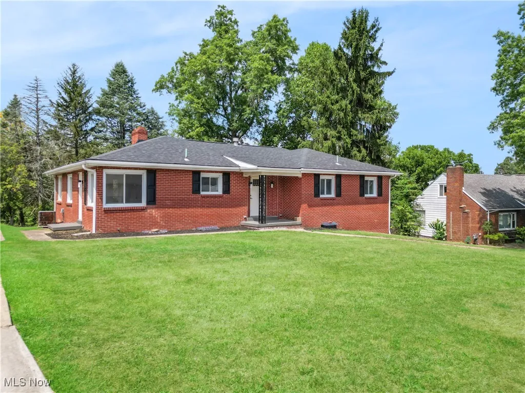 Single story home with brick siding, a chimney, and a front lawn