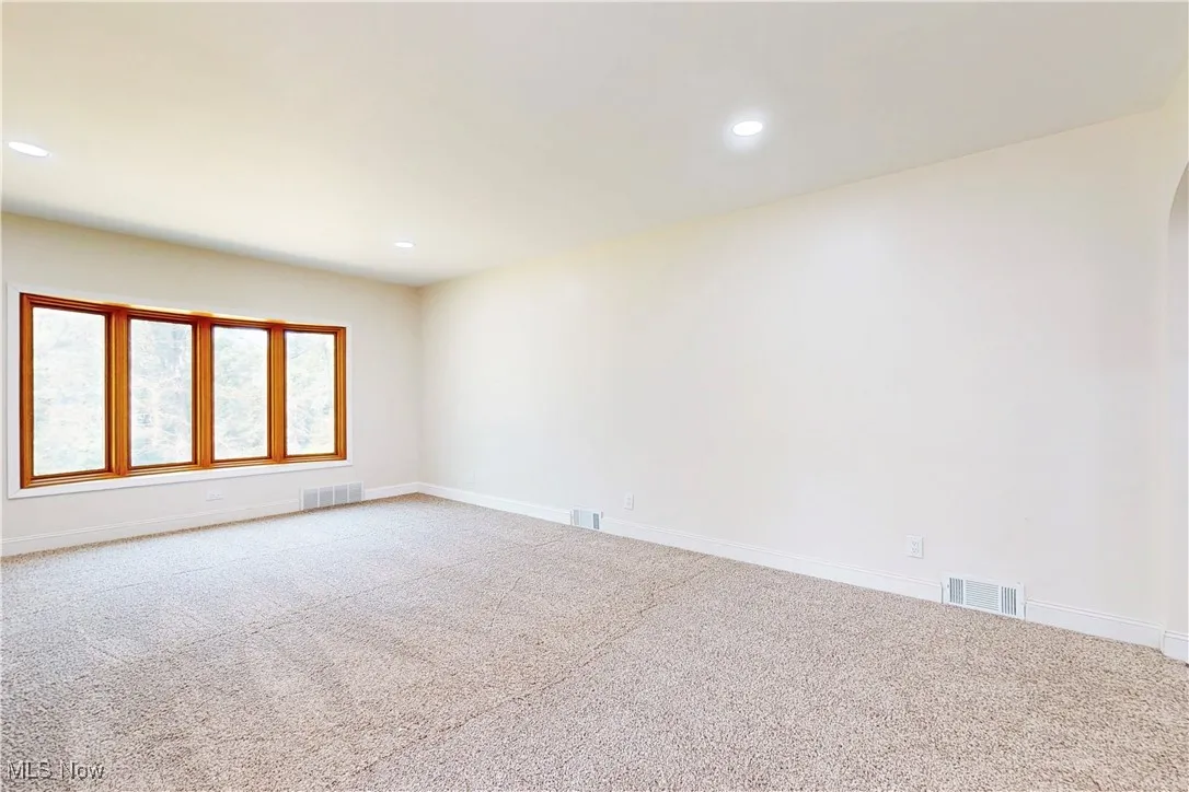 Empty room featuring carpet flooring, recessed lighting, and arched walkways