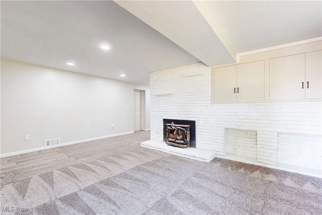 Unfurnished living room with carpet flooring, a brick fireplace, and recessed lighting