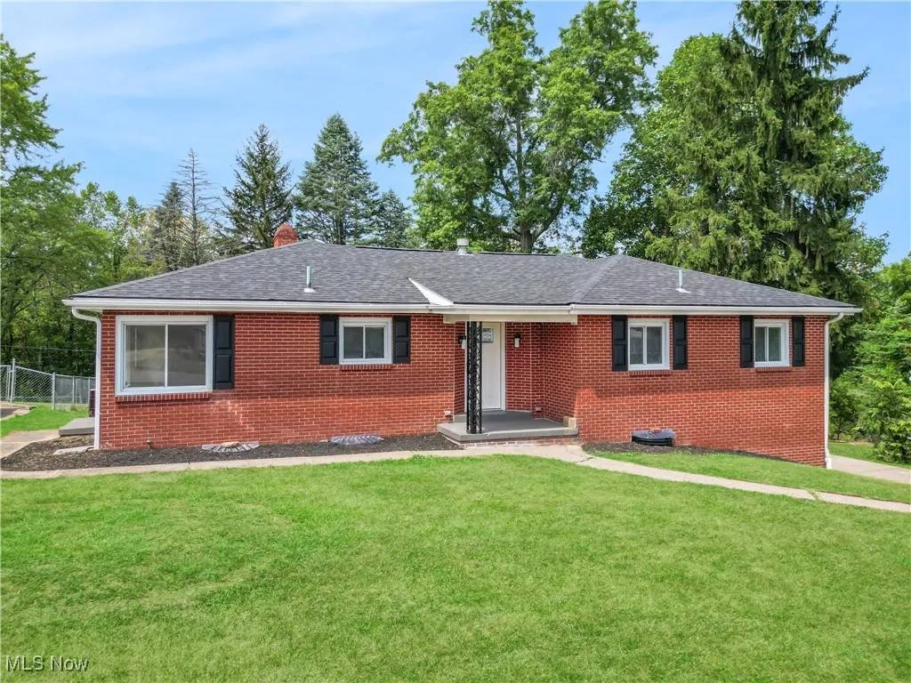 Single story home featuring brick siding, a chimney, and roof with shingles