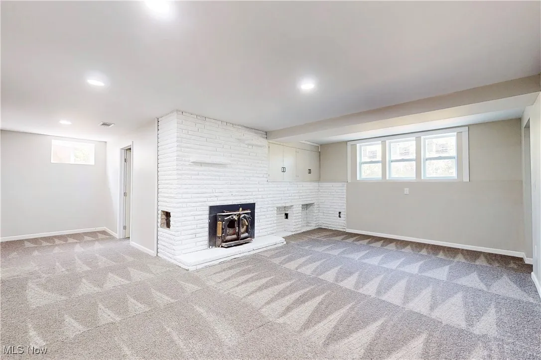 Basement featuring light carpet, a fireplace, and recessed lighting