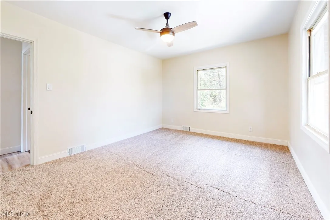 Empty room featuring light carpet and a ceiling fan