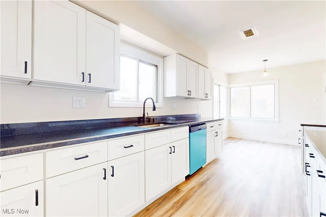 Kitchen with white cabinetry, light wood-type flooring, dishwashing machine, and pendant lighting