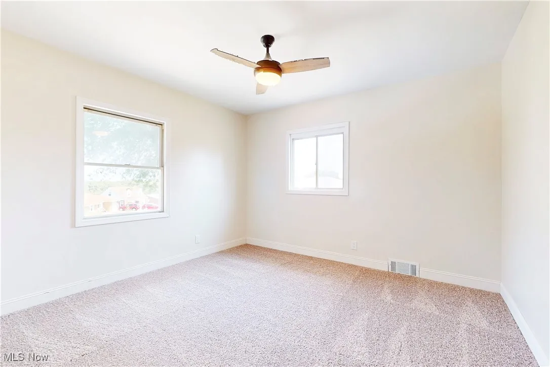 Unfurnished room with light carpet and a ceiling fan