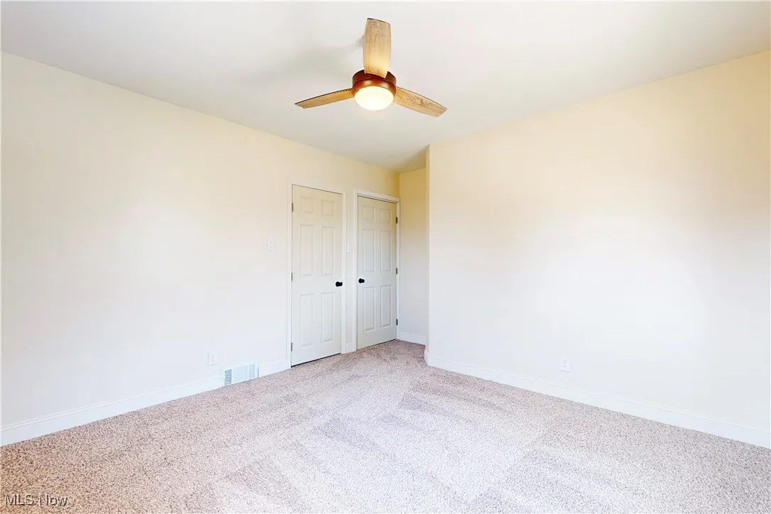 Carpeted spare room with baseboards and ceiling fan