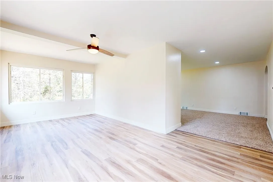 Empty room with light wood finished floors, arched walkways, recessed lighting, and ceiling fan