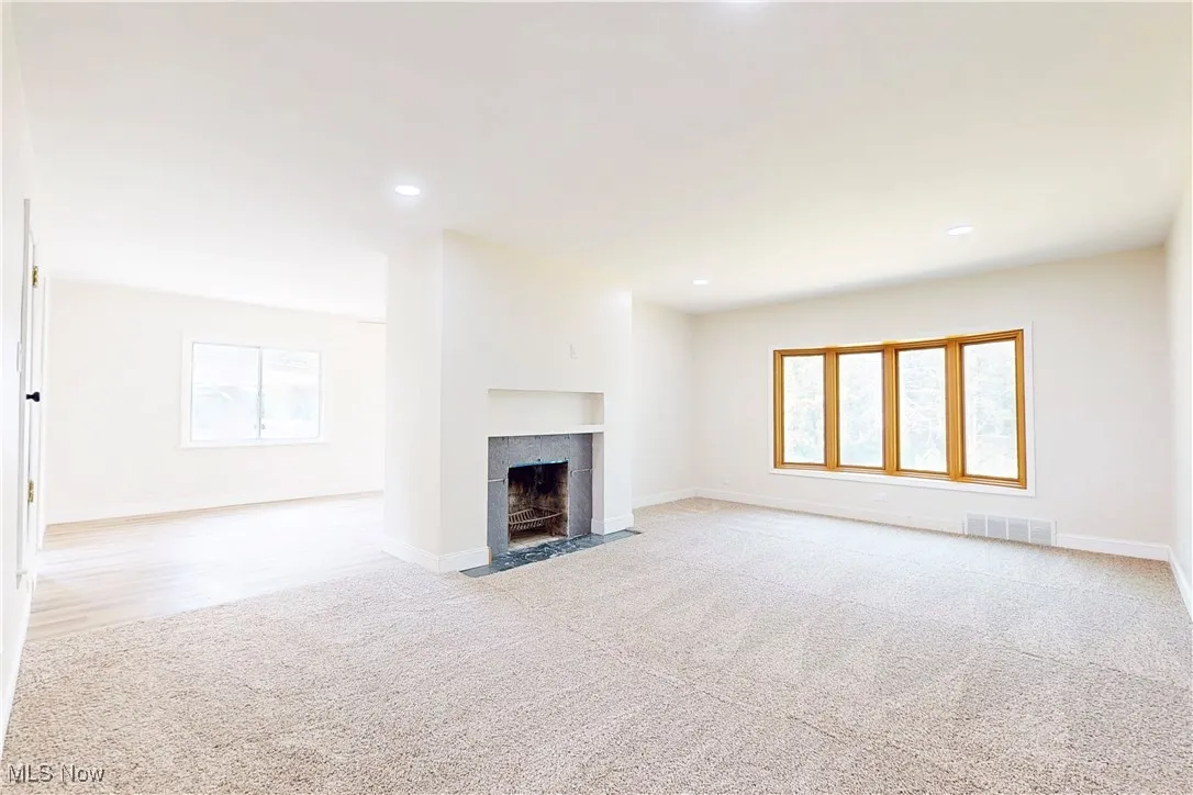 Unfurnished living room with light colored carpet, recessed lighting, and a tile fireplace