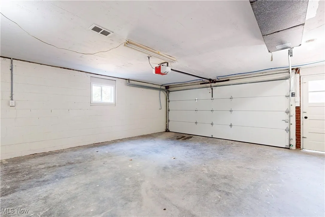 Garage featuring concrete block wall and a garage door opener