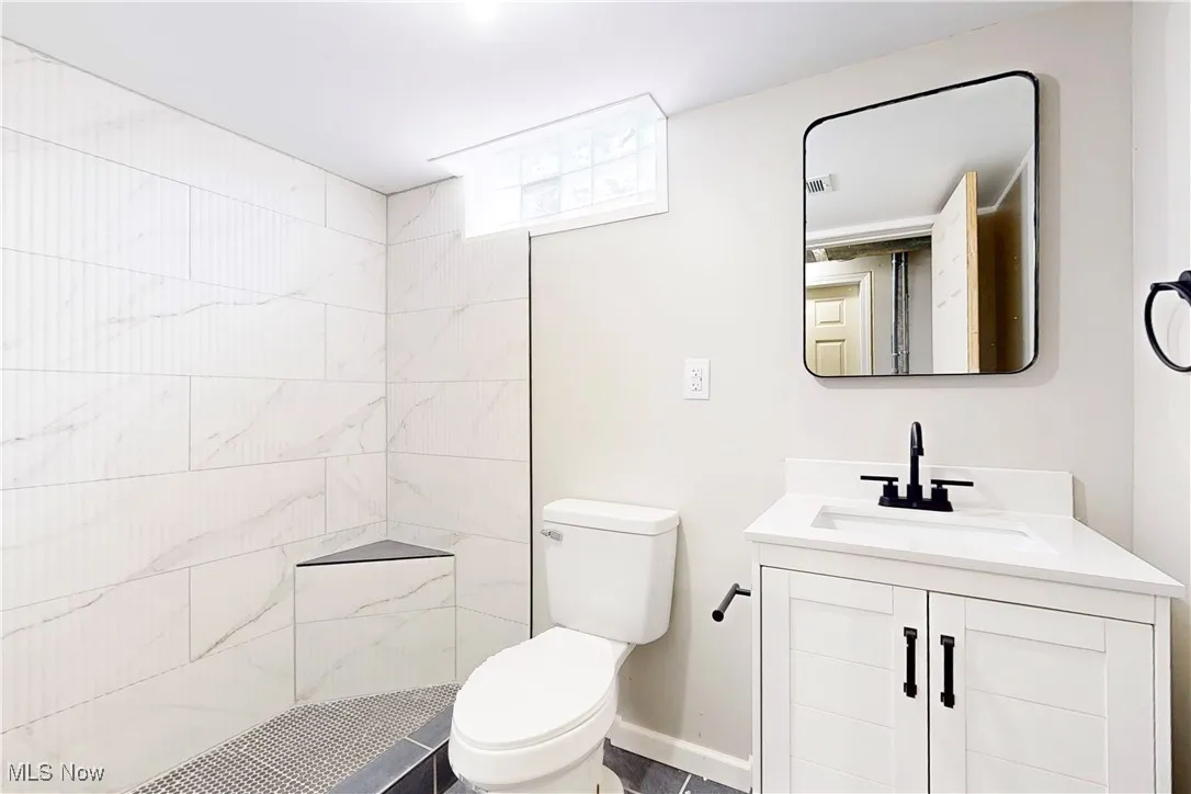 Full bath featuring vanity and tiled shower