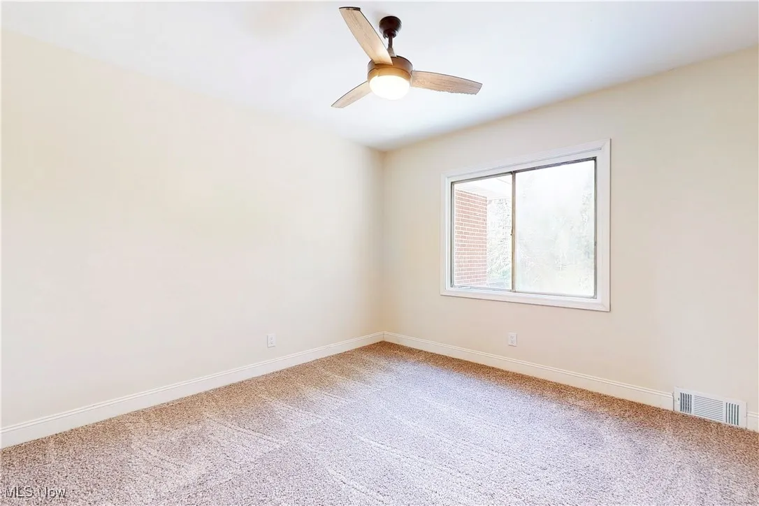 Empty room featuring light colored carpet and ceiling fan