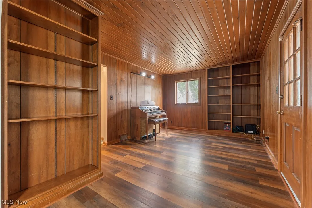 Office with wooden walls, built in features, dark wood-type flooring, and wood ceiling