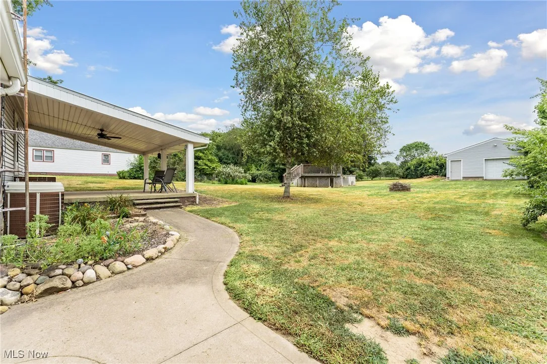 View of grassy yard featuring an outdoor structure and a ceiling fan