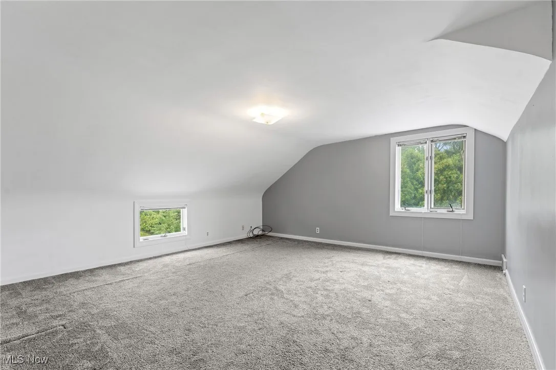 view of large primary bedroom with vaulted ceiling and carpet flooring