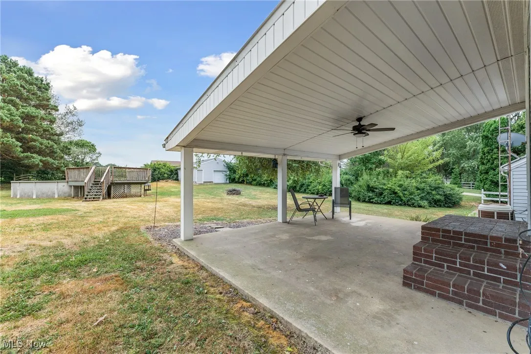 View of patio featuring ceiling fan, stairs, and an outbuilding