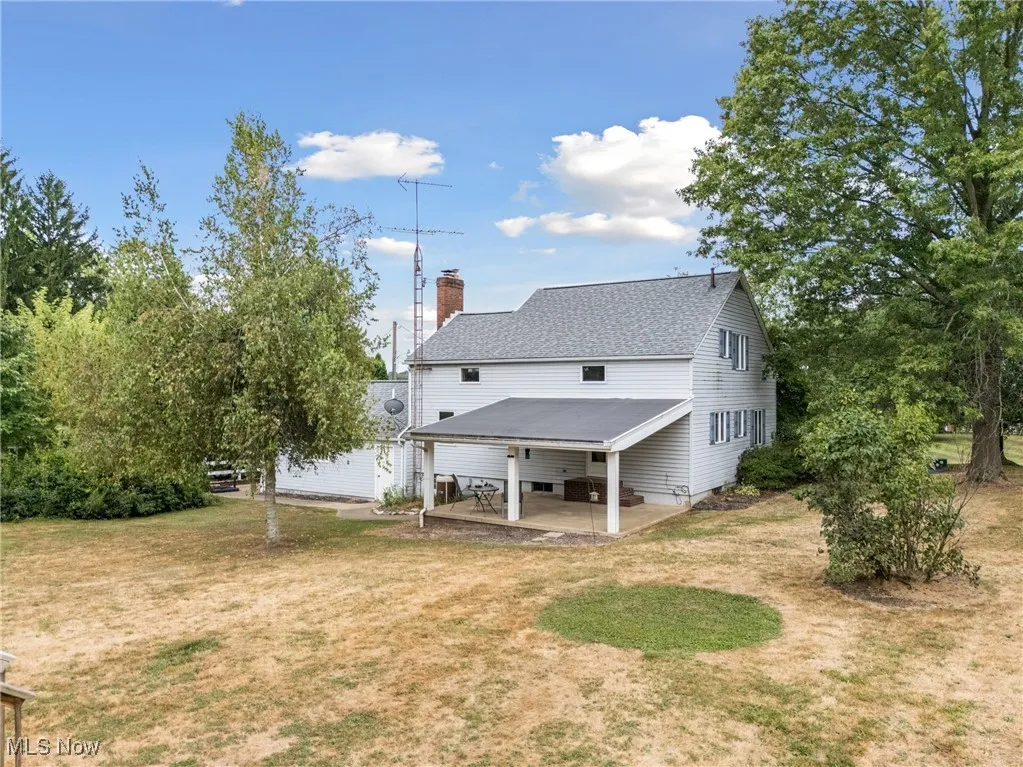 Rear view of house featuring a patio, a chimney, and a yard