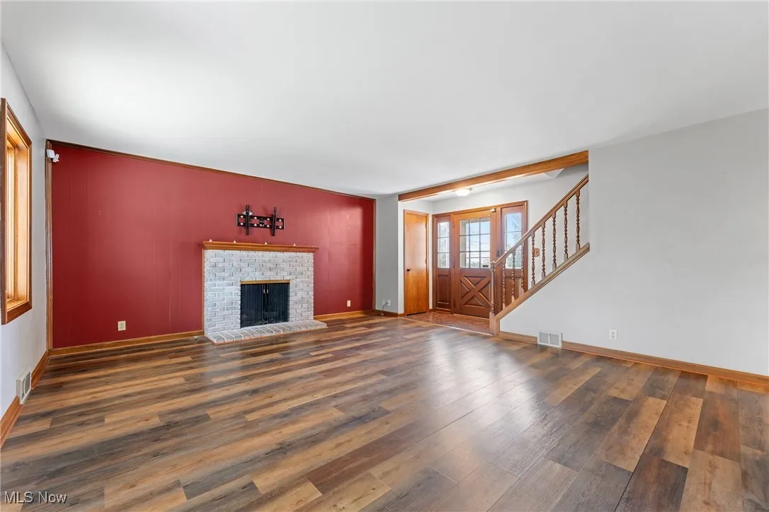 Unfurnished living room featuring stairway, wood finished floors, and a fireplace