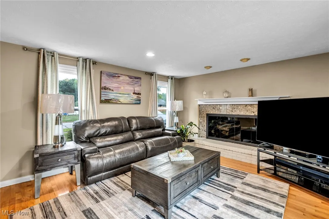 Living area with healthy amount of natural light, light wood-type flooring, a glass covered fireplace, and recessed lighting