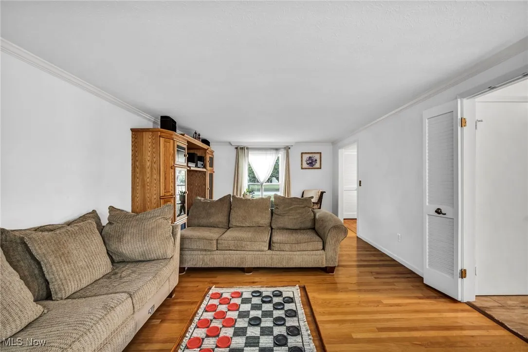 Living area with light wood finished floors and crown molding