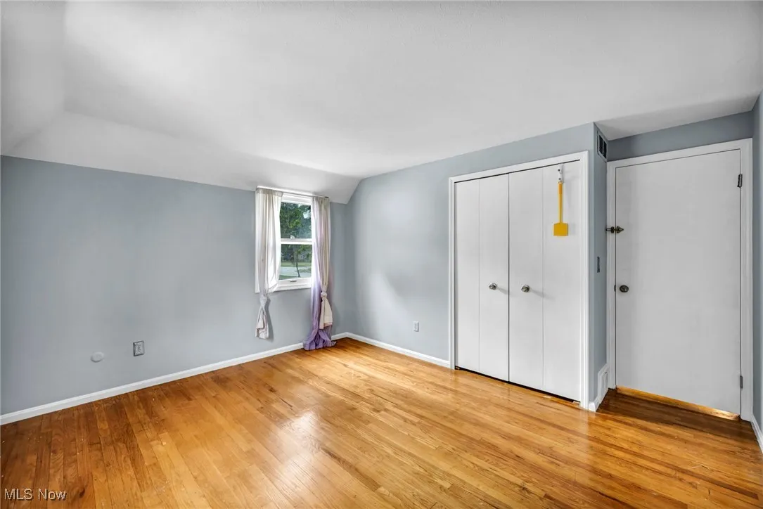 Unfurnished bedroom featuring light wood-style floors, a closet, and lofted ceiling