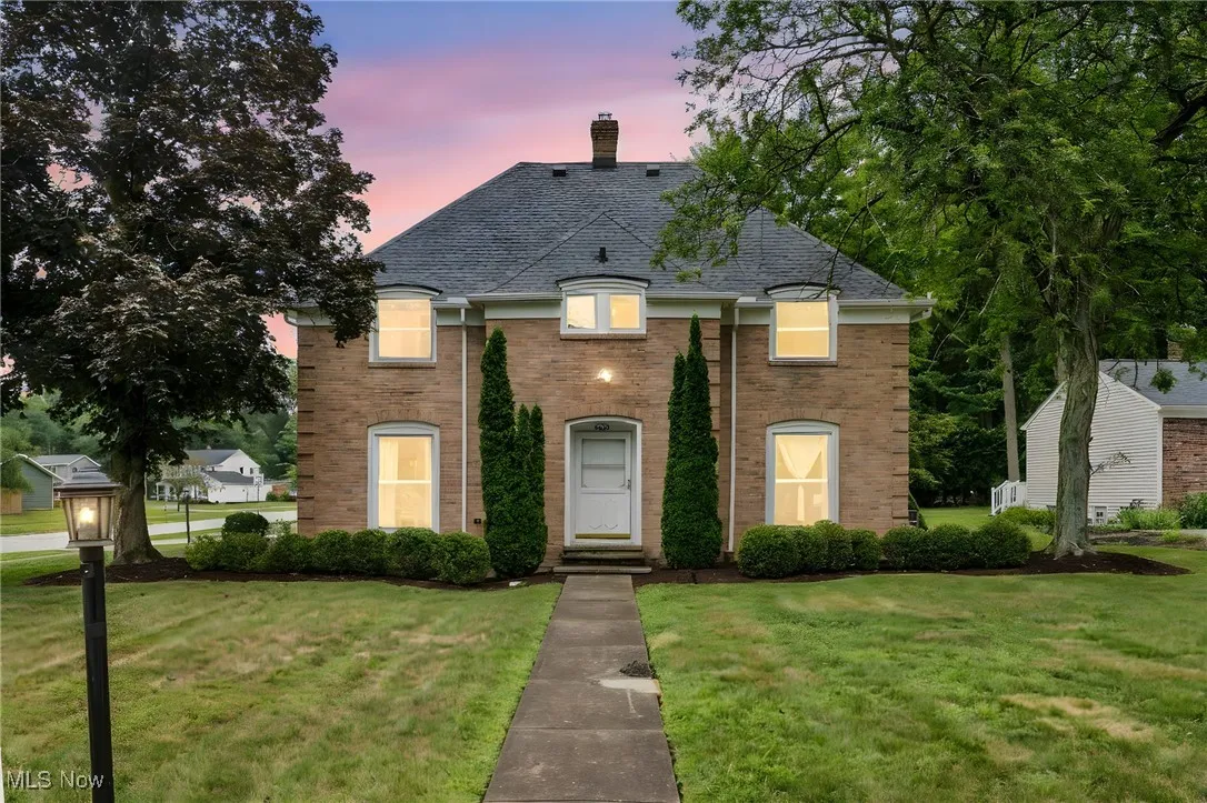 French provincial home featuring brick siding, a lawn, a shingled roof, and a chimney