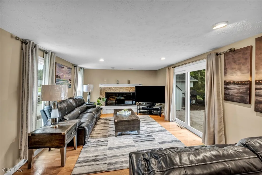 Living room with a glass covered fireplace, light wood-style flooring, healthy amount of natural light, recessed lighting, and a textured ceiling