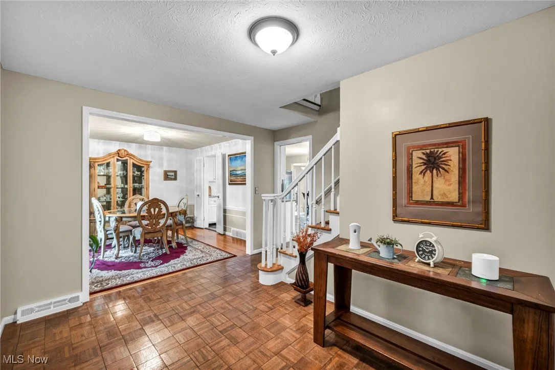 Foyer featuring a textured ceiling, stairway, and parquet floors
