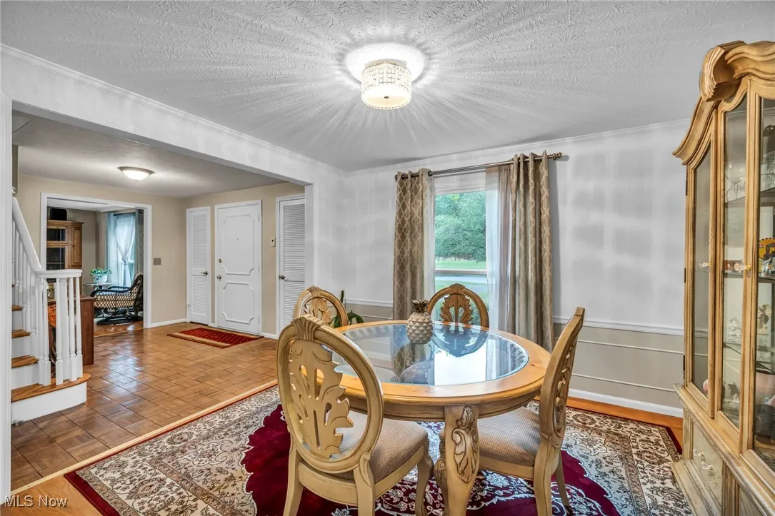 Dining space with a textured ceiling, wood finished floors, and stairs