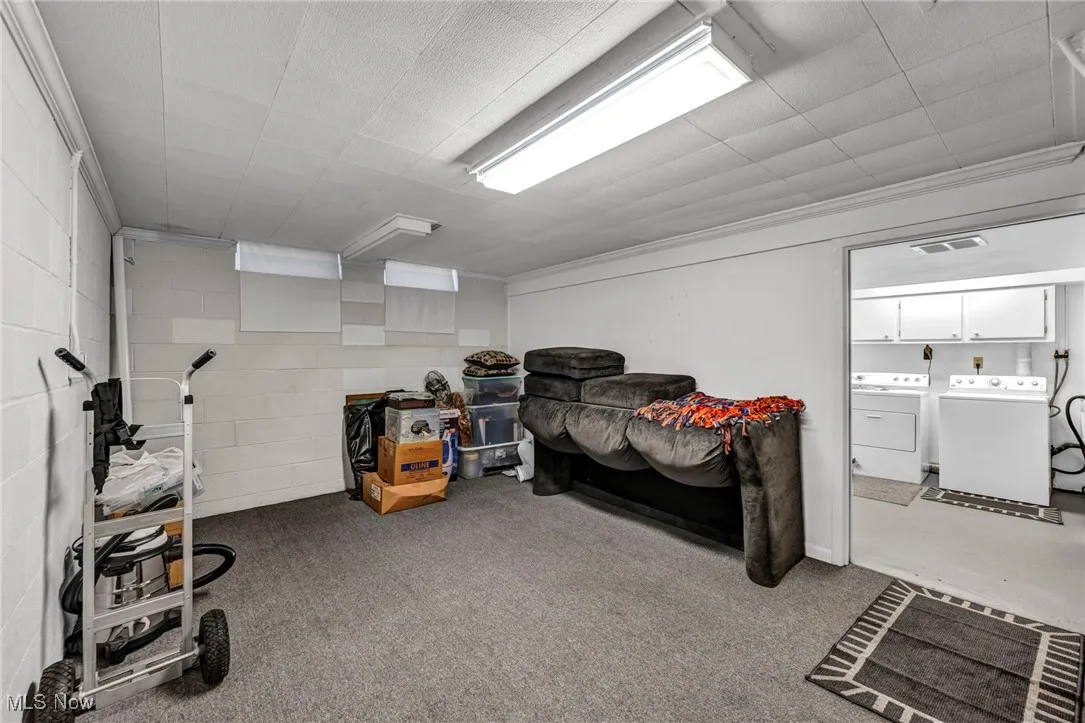 Carpeted bedroom featuring concrete block wall and washing machine and dryer