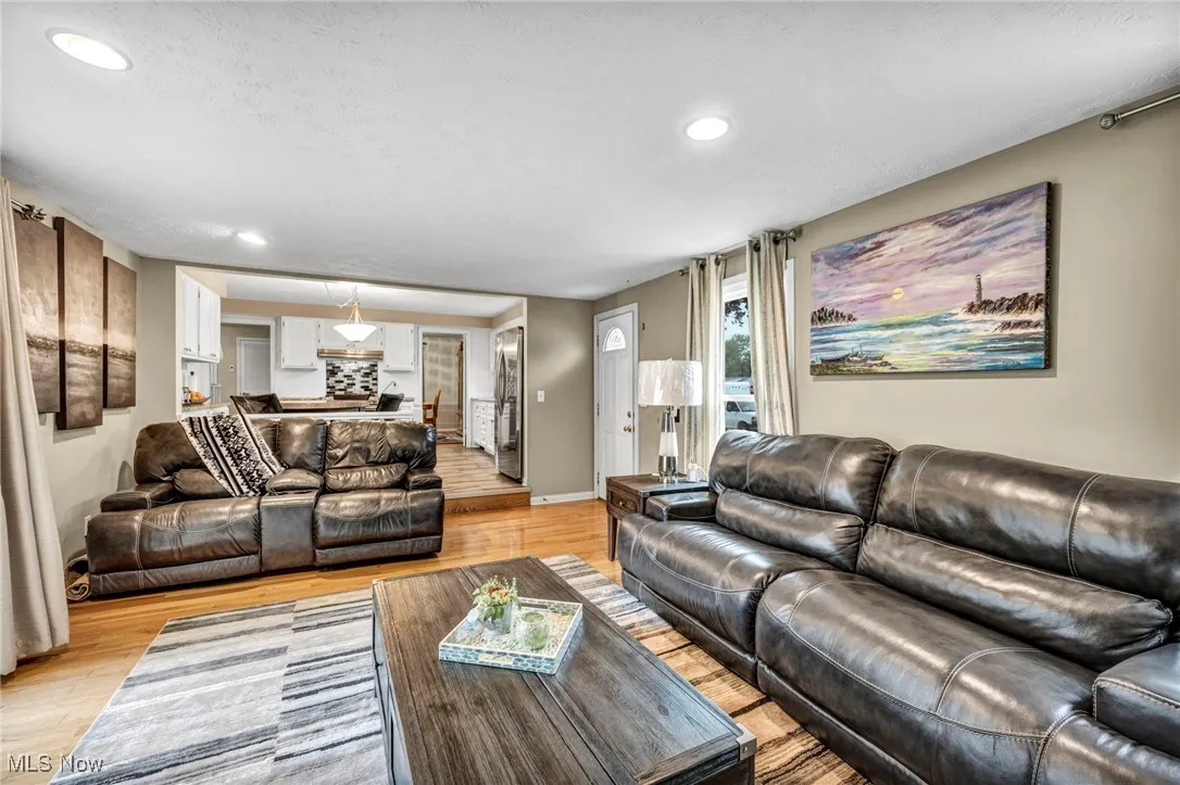 Living room with light wood-style flooring and recessed lighting