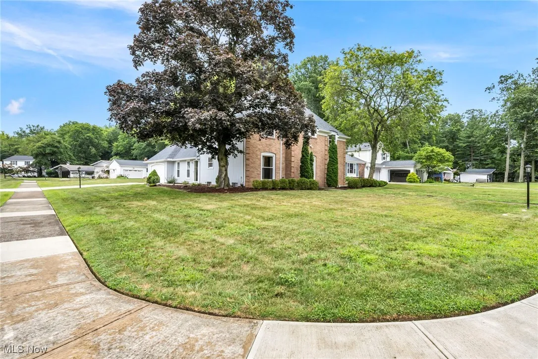 View of front of home with brick siding, a front yard, and a garage