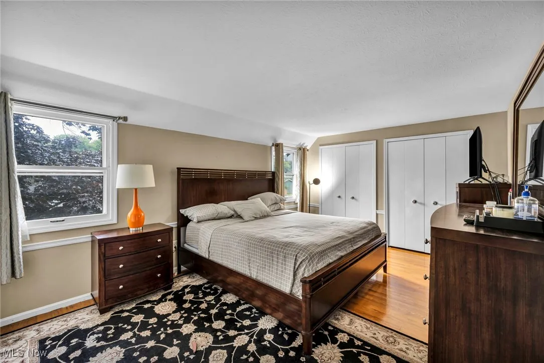 Bedroom featuring two closets, light wood-style flooring, and multiple windows
