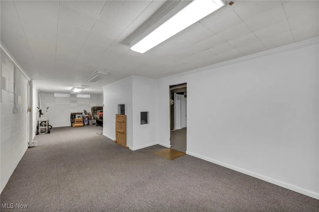 Empty room featuring carpet flooring, ornamental molding, and concrete block wall
