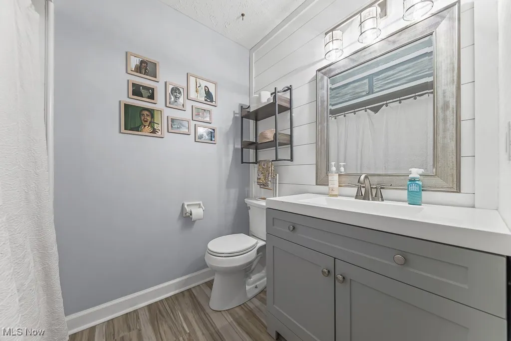 Full bath featuring vanity, light wood-style floors, and curtained shower