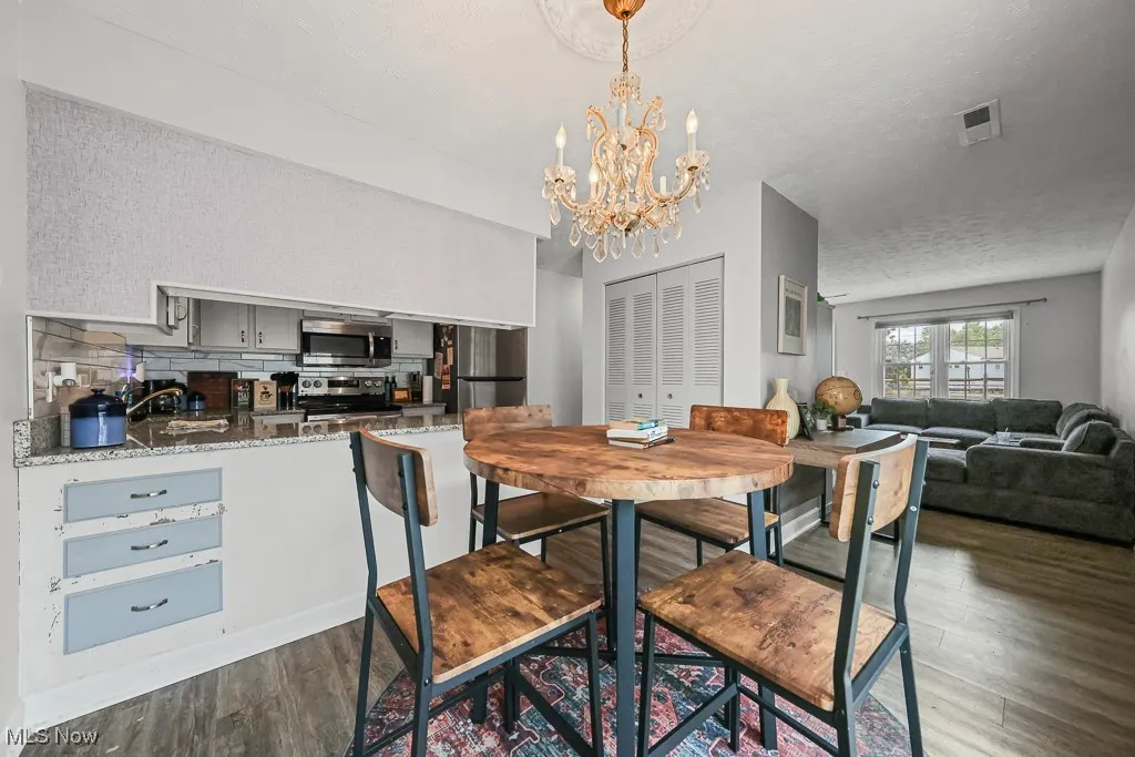 Dining space featuring a textured ceiling, dark wood-type flooring, and a chandelier