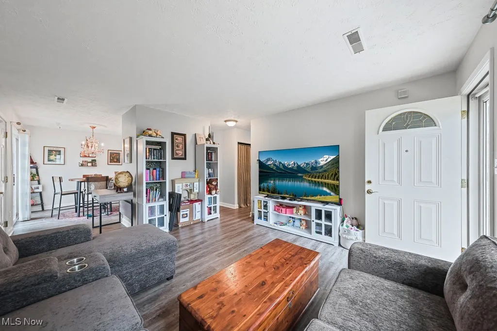 Living area with wood finished floors, a chandelier, and a textured ceiling