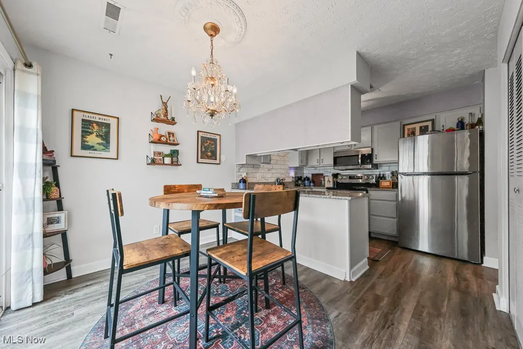 Dining room featuring dark wood-type flooring, a chandelier, and a textured ceiling