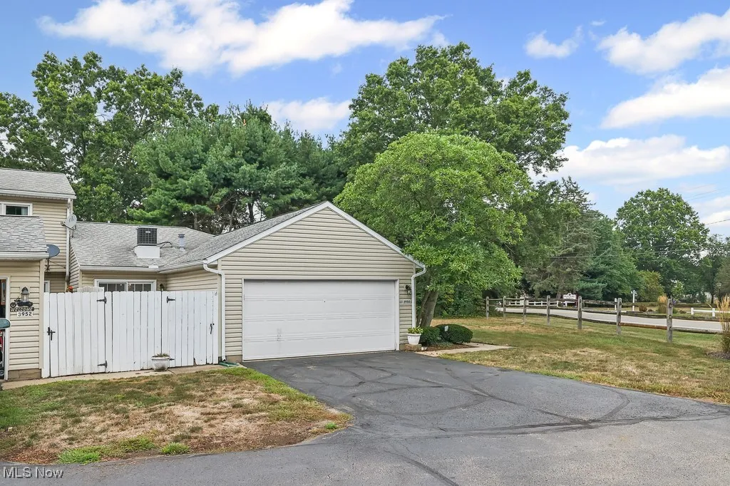 Garage with a gate, asphalt driveway, and view of wooded area