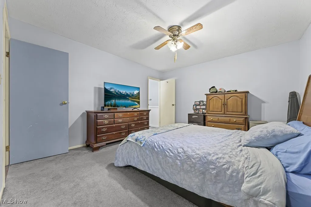 Bedroom featuring light carpet, a ceiling fan, and a textured ceiling
