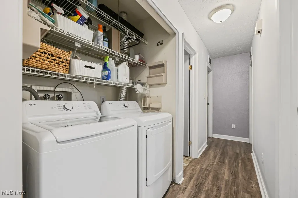 Washroom featuring dark wood finished floors, washer and dryer, and a textured ceiling