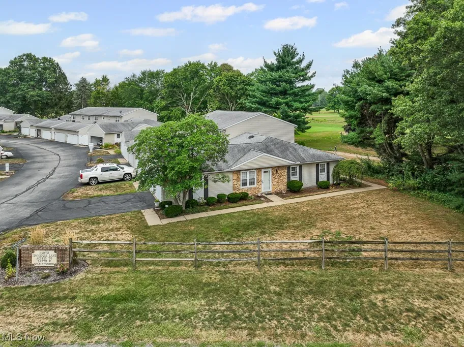 View of front of property featuring driveway, a shingled roof, and view of scattered trees