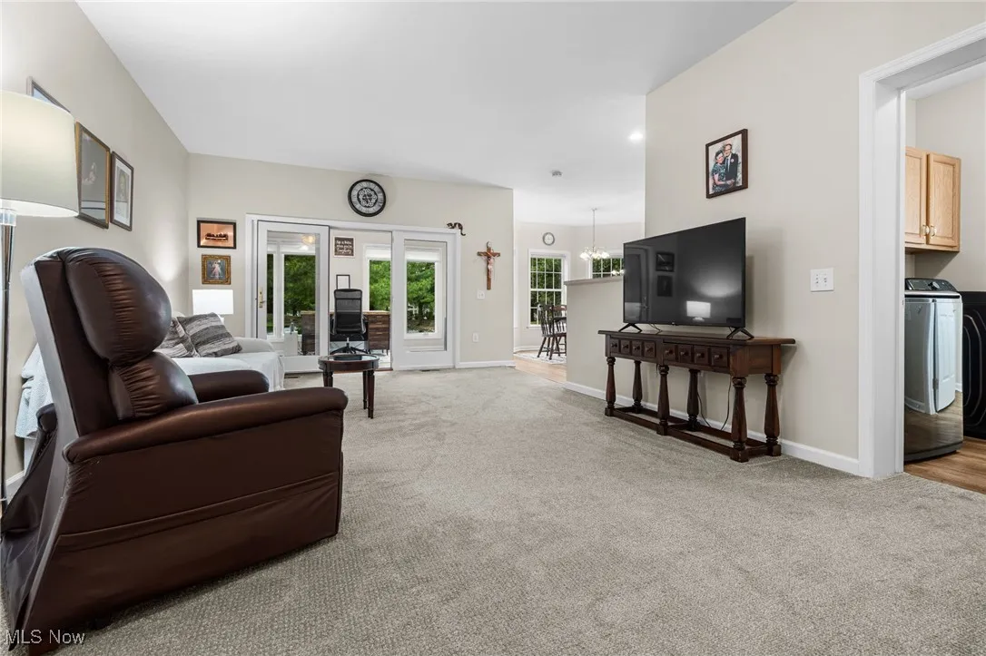 Living room featuring light colored carpet, a chandelier, and washer / clothes dryer
